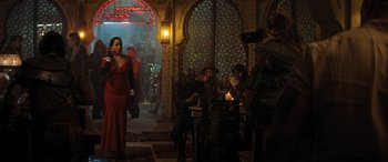 Movie still from “Jumanji: The Next Level” (2019), directed by Jake Kasdan – A group of people sitting at a table in front of a building; Wide shot, Over the shoulder angle