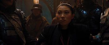 Movie still from “Jumanji: The Next Level” (2019), directed by Jake Kasdan – A woman sitting in front of a group of people; Close Up shot, Over the shoulder angle