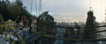 Movie still from “Jumanji: The Next Level” (2019), directed by Jake Kasdan – A person standing on a bridge over a river; Extreme Wide shot, Low angle
