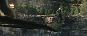 Movie still from “Jumanji: The Next Level” (2019), directed by Jake Kasdan – A man standing on top of a bridge over a body of water; Wide shot, High angle