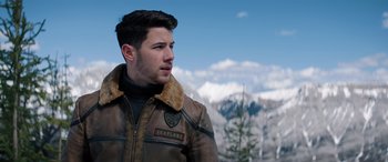 Movie still from “Jumanji: The Next Level” (2019), directed by Jake Kasdan – A man wearing a brown leather jacket standing in front of snow covered mountains; Close Up shot, Over the shoulder angle