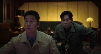 Movie still from “Jung_E” (2023), directed by Yeon Sang-ho – Two asian men are sitting in front of each other in a restaurant; Medium shot, Over the shoulder angle