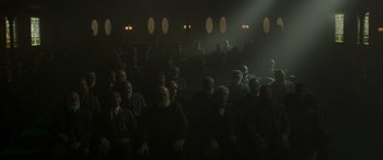 Movie still from “Jungle Cruise” (2021), directed by Jaume Collet-Serra – A group of people sitting in a dark room; Wide shot, High angle