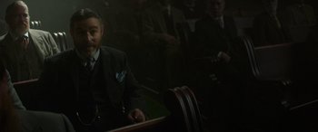 Movie still from “Jungle Cruise” (2021), directed by Jaume Collet-Serra – A man in a suit sitting in front of other men; Medium shot, Low angle