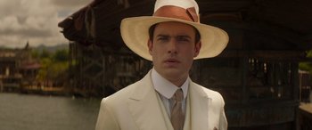 Movie still from “Jungle Cruise” (2021), directed by Jaume Collet-Serra – A man in a white suit and a brown hat; Close Up shot, Over the shoulder angle