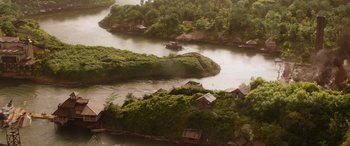 Movie still from “Jungle Cruise” (2021), directed by Jaume Collet-Serra – An aerial view of houses on a river bank; Extreme Wide shot, High angle