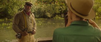 Movie still from “Jungle Cruise” (2021), directed by Jaume Collet-Serra – A man and a woman standing next to a body of water; Medium shot, Over the shoulder angle