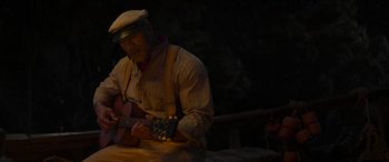 Movie still from “Jungle Cruise” (2021), directed by Jaume Collet-Serra – A man playing a guitar in the dark; Medium shot, High angle