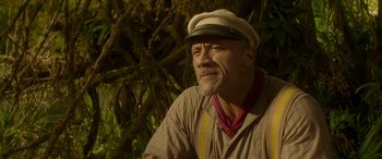 Movie still from “Jungle Cruise” (2021), directed by Jaume Collet-Serra – A man wearing a hat sitting in front of a tree; Close Up shot, Over the shoulder angle