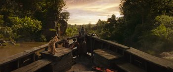 Movie still from “Jungle Cruise” (2021), directed by Jaume Collet-Serra – A man sitting on a bench next to a cat; Extreme Wide shot, Low angle