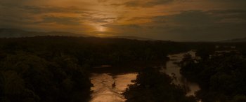 Movie still from “Jungle Cruise” (2021), directed by Jaume Collet-Serra – A person in the water at sunset with trees in the background; Extreme Wide shot, High angle