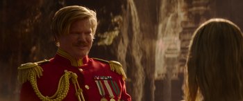 Movie still from “Jungle Cruise” (2021), directed by Jaume Collet-Serra – A man in a red military uniform stands in front of a rock wall; Close Up shot, Over the shoulder angle