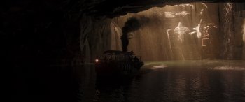 Movie still from “Jungle Cruise” (2021), directed by Jaume Collet-Serra – A boat in the middle of a lake near a cave; Extreme Wide shot, High angle