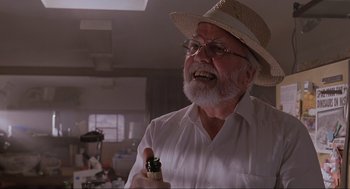 Movie still from “Jurassic Park” (1993), directed by Steven Spielberg – An old man with a beard and a hat is holding a bottle; Close Up shot, Low angle