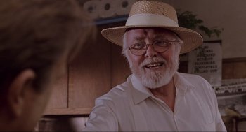 Movie still from “Jurassic Park” (1993), directed by Steven Spielberg – An older man wearing a straw hat and glasses; Close Up shot, Over the shoulder angle