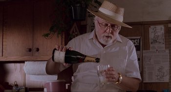Movie still from “Jurassic Park” (1993), directed by Steven Spielberg – An older man pouring a glass of wine into a wine glass; Close Up shot, Low angle