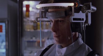Movie still from “Jurassic Park” (1993), directed by Steven Spielberg – A man wearing a face shield in a store; Close Up shot, Over the shoulder angle