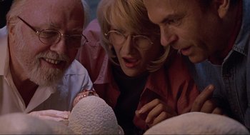 Movie still from “Jurassic Park” (1993), directed by Steven Spielberg – A group of people looking at something on a table; Close Up shot, High angle