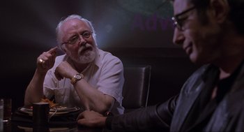 Movie still from “Jurassic Park” (1993), directed by Steven Spielberg – A man sitting at a table in front of another man; Close Up shot, Over the shoulder angle