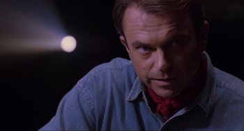 Movie still from “Jurassic Park” (1993), directed by Steven Spielberg – A person wearing a blue shirt and a red neck tie; Close Up shot, Over the shoulder angle