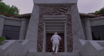 Movie still from “Jurassic Park” (1993), directed by Steven Spielberg – A man walking up a flight of stairs in front of a building; Extreme Wide shot, Low angle