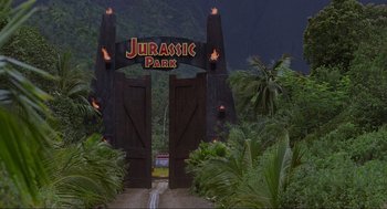 Movie still from “Jurassic Park” (1993), directed by Steven Spielberg – The entrance to the jurassic park theme park is lit up; Extreme Wide shot, High angle