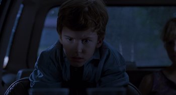Movie still from “Jurassic Park” (1993), directed by Steven Spielberg – A young boy sitting in the back seat of a car; Close Up shot, Over the shoulder angle