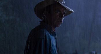 Movie still from “Jurassic Park” (1993), directed by Steven Spielberg – A man wearing a cowboy hat standing in the rain; Close Up shot, Over the shoulder angle