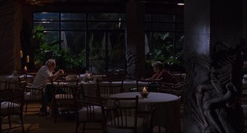 Movie still from “Jurassic Park” (1993), directed by Steven Spielberg – A woman sitting at a table in a restaurant; Wide shot, High angle