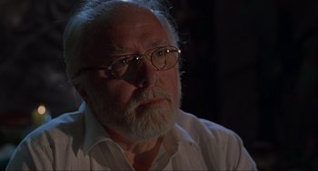 Movie still from “Jurassic Park” (1993), directed by Steven Spielberg – An old man with a beard wearing glasses; Close Up shot, Over the shoulder angle