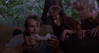 Movie still from “Jurassic Park” (1993), directed by Steven Spielberg – A man and a boy holding a bone in a wooded area; Close Up shot, Over the shoulder angle