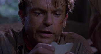 Movie still from “Jurassic Park” (1993), directed by Steven Spielberg – A person holding a piece of food; Close Up shot, Over the shoulder angle