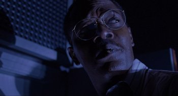 Movie still from “Jurassic Park” (1993), directed by Steven Spielberg – A person wearing glasses and a tie; Close Up shot, Low angle
