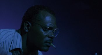 Movie still from “Jurassic Park” (1993), directed by Steven Spielberg – A person wearing glasses and smoking a cigarette; Close Up shot, Low angle