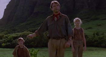 Movie still from “Jurassic Park” (1993), directed by Steven Spielberg – A man and two children standing in the grass; Medium shot, Low angle