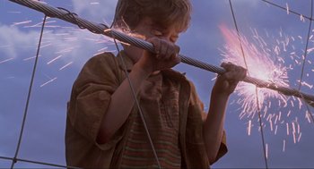Movie still from “Jurassic Park” (1993), directed by Steven Spielberg – A young boy is holding a metal stick; Medium shot, Low angle