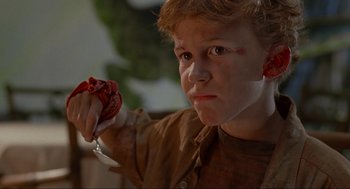 Movie still from “Jurassic Park” (1993), directed by Steven Spielberg – A young boy holding a knife in his hand; Close Up shot, High angle