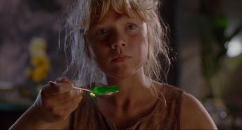 Movie still from “Jurassic Park” (1993), directed by Steven Spielberg – A young girl is holding a green lollipop in her mouth; Close Up shot, Low angle