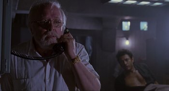 Movie still from “Jurassic Park” (1993), directed by Steven Spielberg – An older man talking on a phone in a dark room; Close Up shot, Low angle