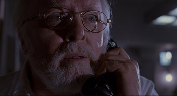 Movie still from “Jurassic Park” (1993), directed by Steven Spielberg – An old man with glasses talking on a phone; Close Up shot, Low angle