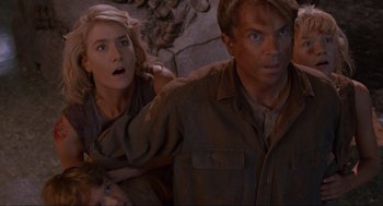 Movie still from “Jurassic Park” (1993), directed by Steven Spielberg – A man and a woman and a child in a cave; Medium shot, High angle