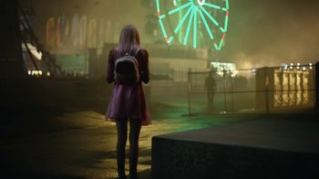A woman standing in front of a ferris wheel at night