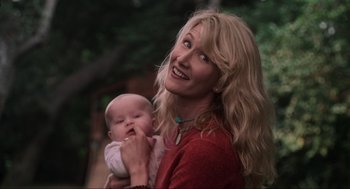Movie still from “Jurassic Park III” (2001), directed by Joe Johnston – A woman holding a baby in her arms and smiling; Close Up shot, Low angle