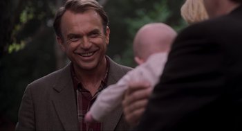 Movie still from “Jurassic Park III” (2001), directed by Joe Johnston – A man smiling while holding a baby in his arms; Close Up shot, Over the shoulder angle