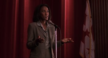 Movie still from “Jurassic Park III” (2001), directed by Joe Johnston – A woman standing on a stage holding a microphone; Close Up shot, Low angle