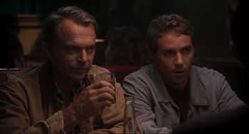 Movie still from “Jurassic Park III” (2001), directed by Joe Johnston – Two men sitting next to each other holding a drink; Close Up shot, Over the shoulder angle