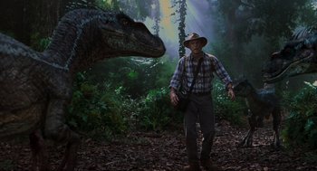 Movie still from “Jurassic Park III” (2001), directed by Joe Johnston – A man in a hat is standing next to a dinosaur; Wide shot, Low angle