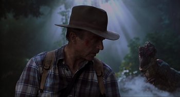 Movie still from “Jurassic Park III” (2001), directed by Joe Johnston – A person wearing a hat with trees in the background; Medium shot, Low angle