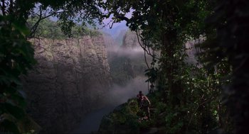 Movie still from “Jurassic Park III” (2001), directed by Joe Johnston – A man standing on top of a cliff next to a body of water; Extreme Wide shot, High angle