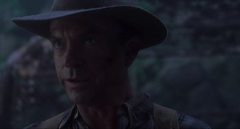 Movie still from “Jurassic Park III” (2001), directed by Joe Johnston – A person wearing a hat with trees in the background; Close Up shot, Over the shoulder angle